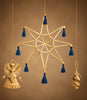 A hanging gold-toned star ornament with blue tassels, shown against a warm brown background. Smaller hanging ornaments in gold tones are visible at the lower left and lower right.