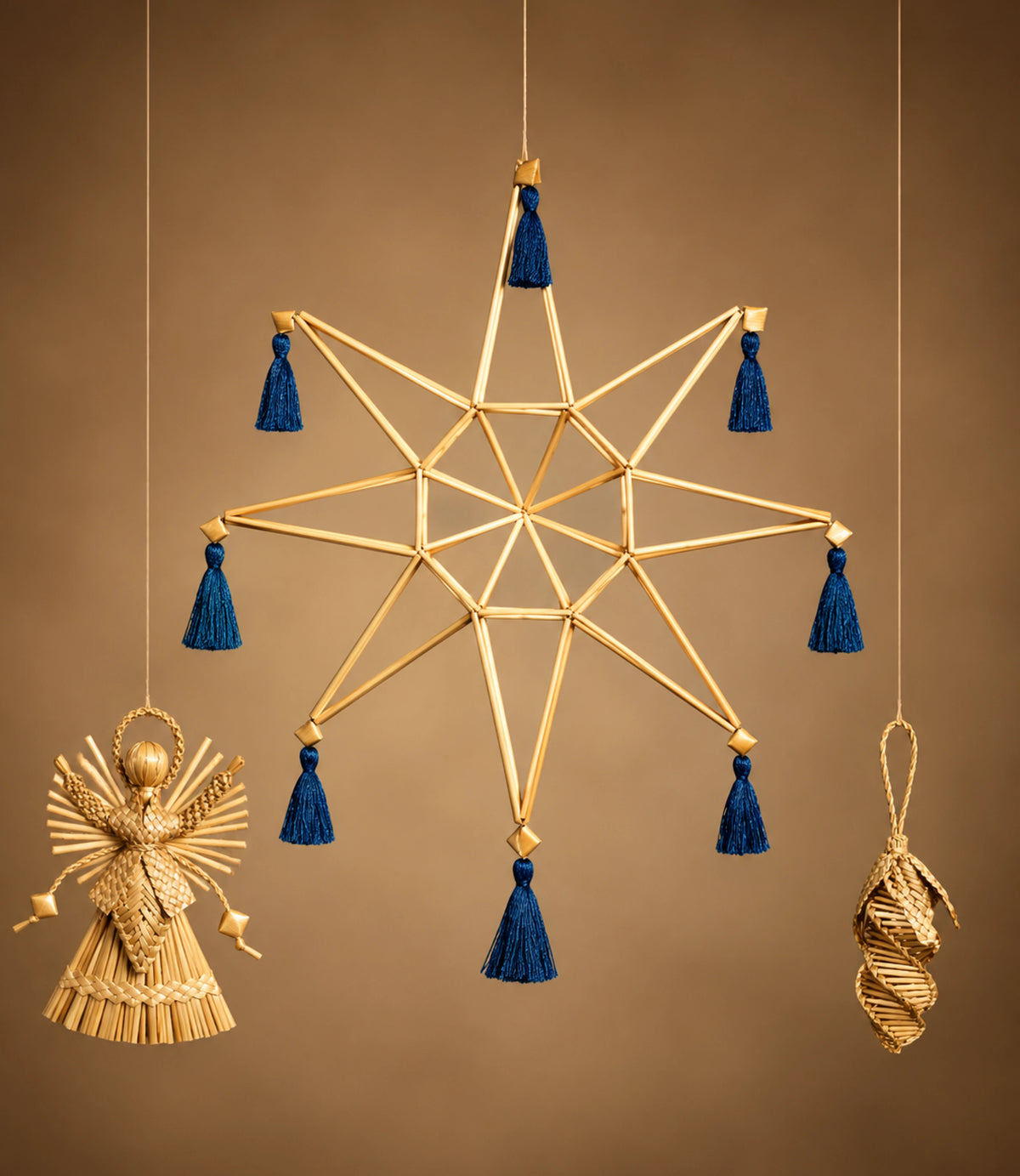 A hanging gold-toned star ornament with blue tassels, shown against a warm brown background. Smaller hanging ornaments in gold tones are visible at the lower left and lower right.